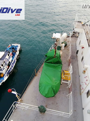 commercial diving support vessel alongside cargo ship during underwater maintenance