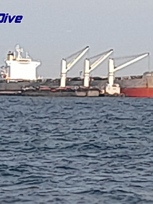 Commercial vessel at anchorage in Thailand during hull cleaning and propeller polishing operation.