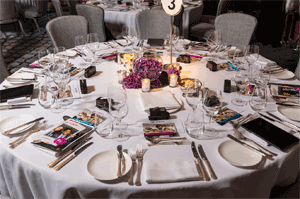 A circular table with white tablecloth set for eight people