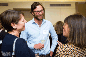 Man in glasses talking to two women