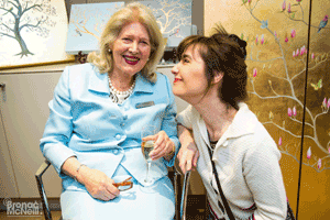 Two women smiling in front of artworks