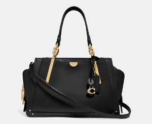 A designer handbag by Coach in black leather with gold hardware and a signature charm