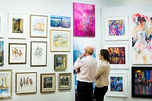 Man and woman looking at a wall of paintings
