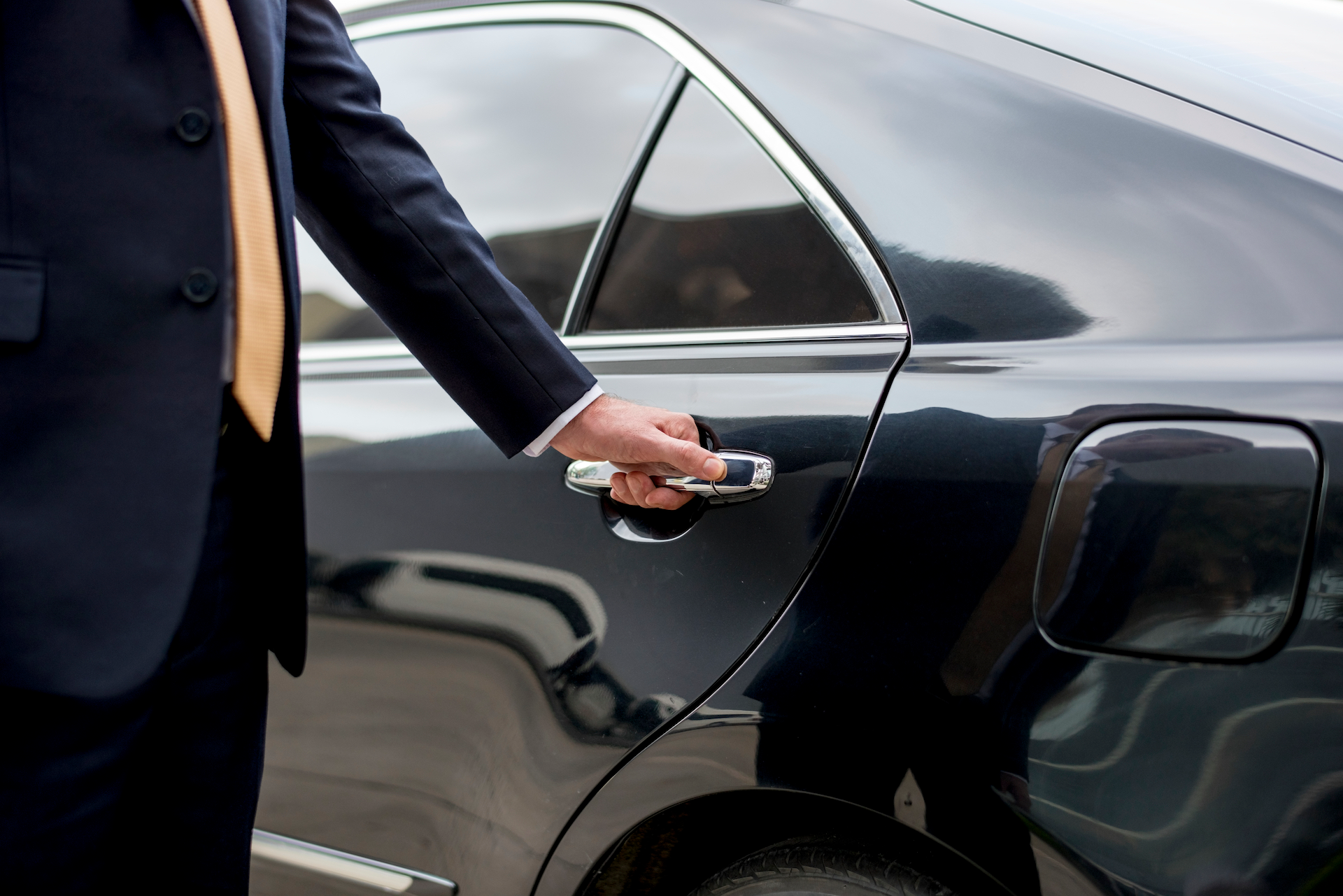 chauffeur opening a limousine door for a client