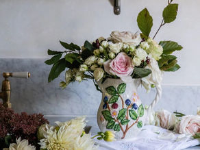 Spring floral arrangement in handmade vase in kitchen with marble countertops and butter yellow cabinets