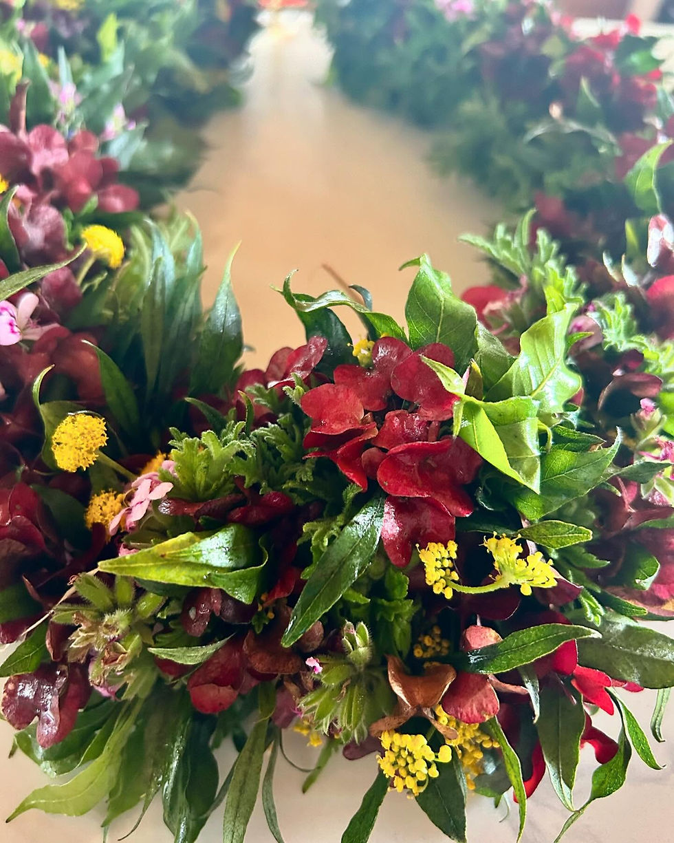 A beautifully crafted Lei Po'o showcasing vibrant red, yellow, and green foliage, intricately woven using the traditional wili method.