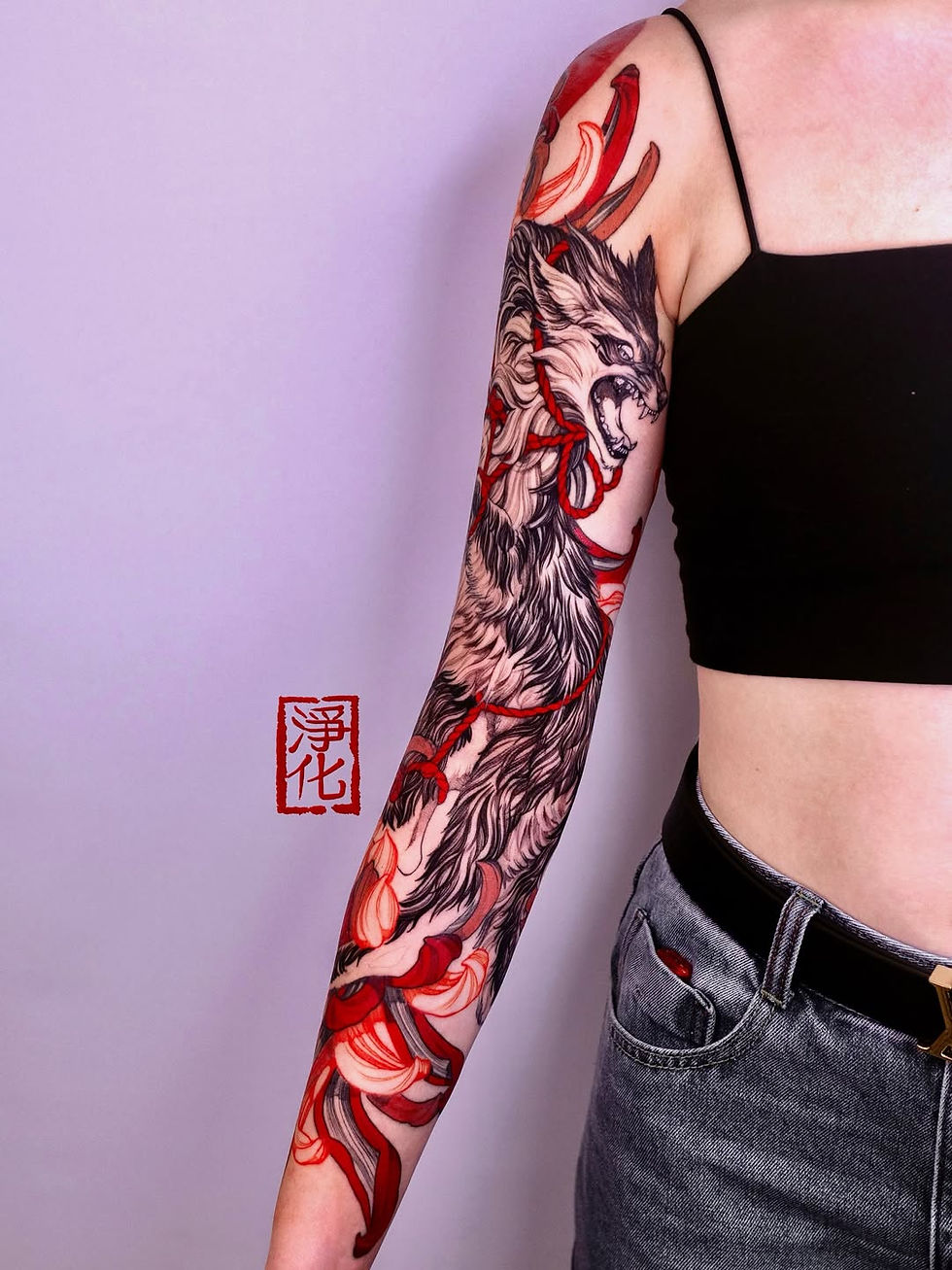 Person with a detailed red and black tattoo of a snarling wolf on their arm. They're wearing a black top and jeans. Asian characters in red.