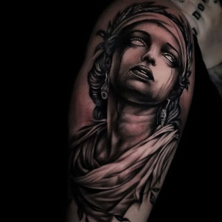 black and grey realism tattoo upper arm divine woman portrait with white eyes and draped fabric by Graham O’Gorman Hammersmith Tattoo London realistic goddess design