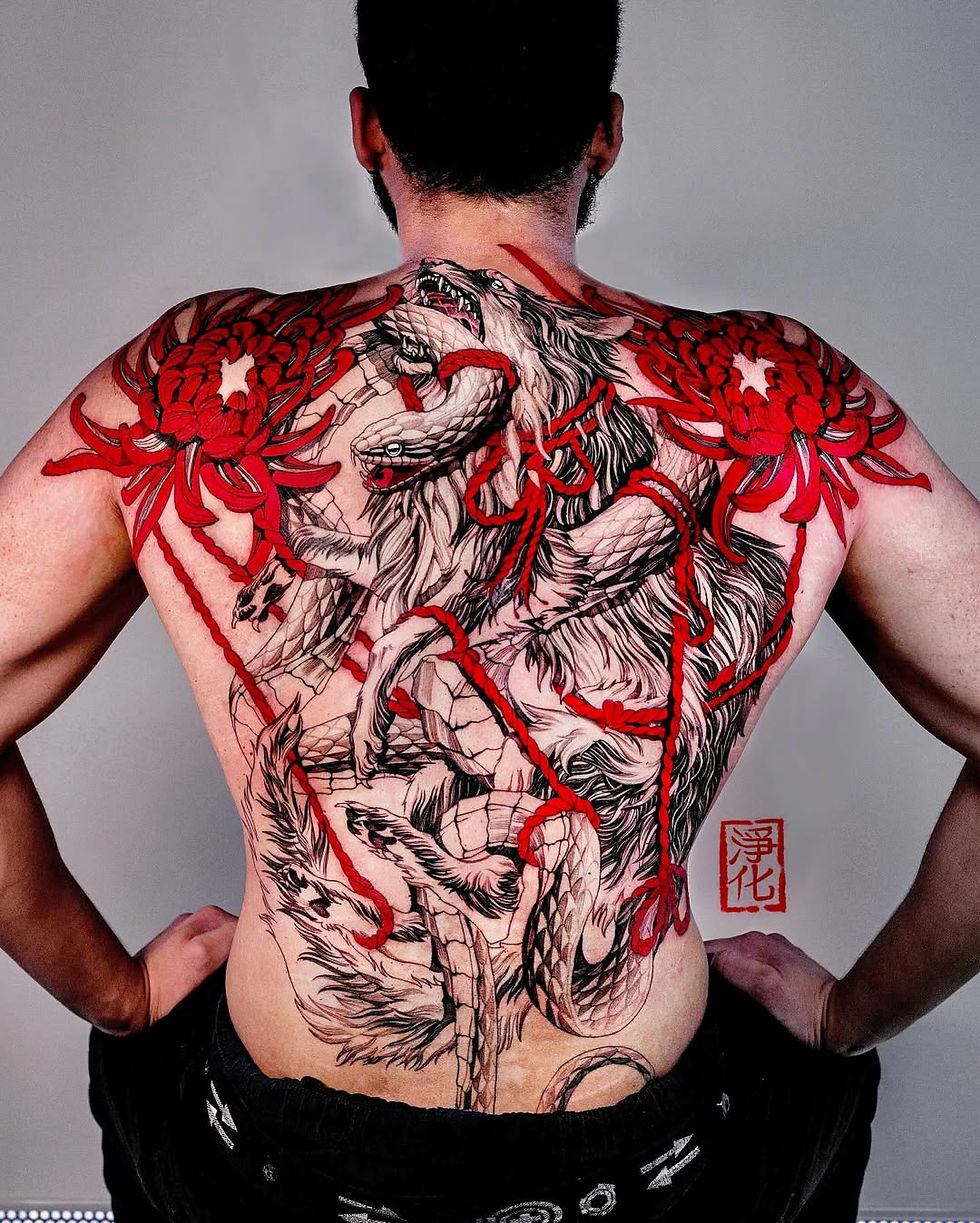 Man's back with a detailed tattoo of wolves, a snake, and red flowers. Bold red accents and kanji text on a light background.
