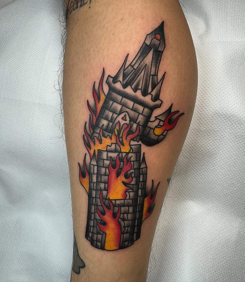 Tattoo of a burning castle with gray bricks and red-orange flames on a person's arm, set against a white background.