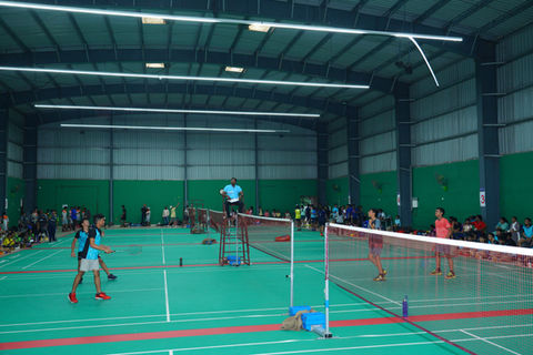 Students playing badminton in a sports hall during a school competition.