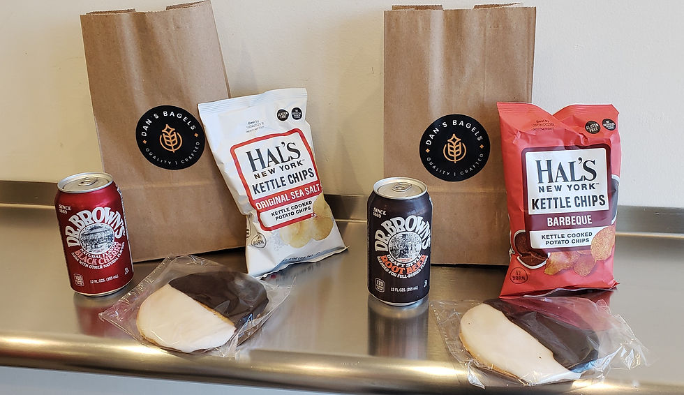 sodas, bags of chips and black and white cookies with lunch bags holding bagels