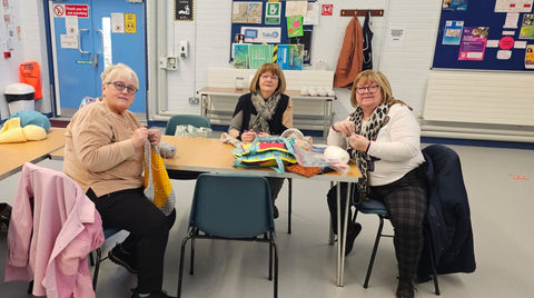 Three women crocheting at a table