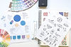 Flat lay photo of a logo branding guide, color wheel, sketchbook and markers