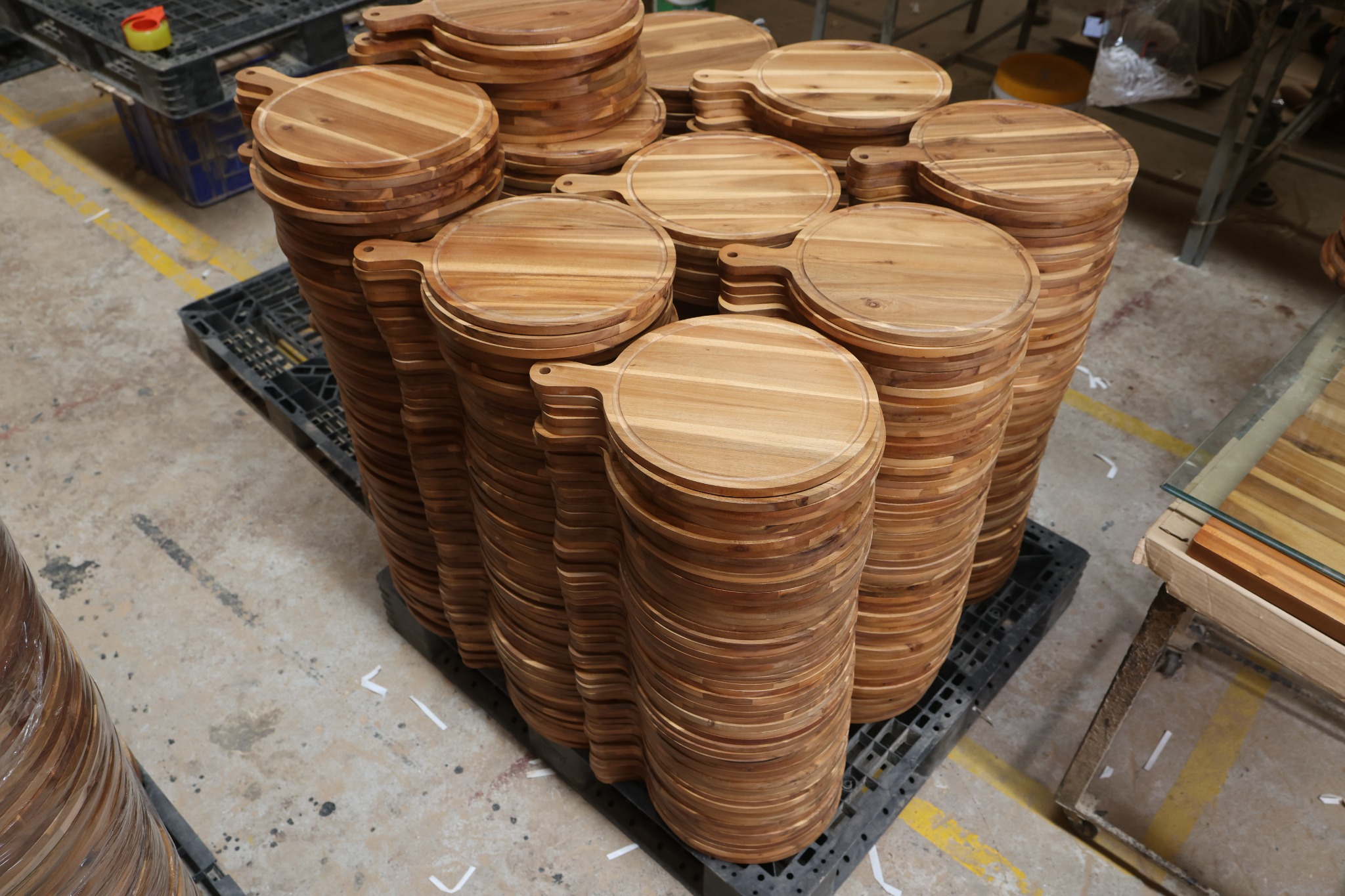 Stacks of round wooden paddle serving boards in our factory