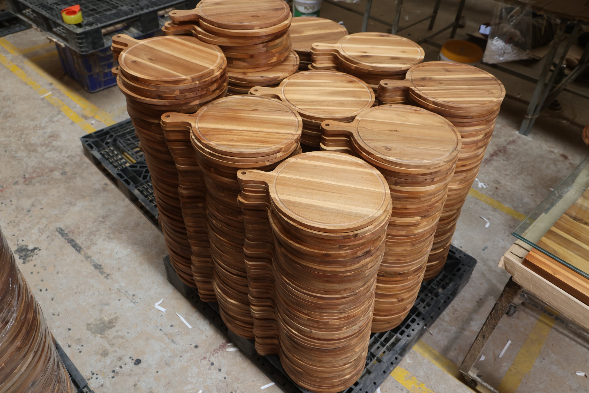 Round wooden paddle serving boards stacked during factory production