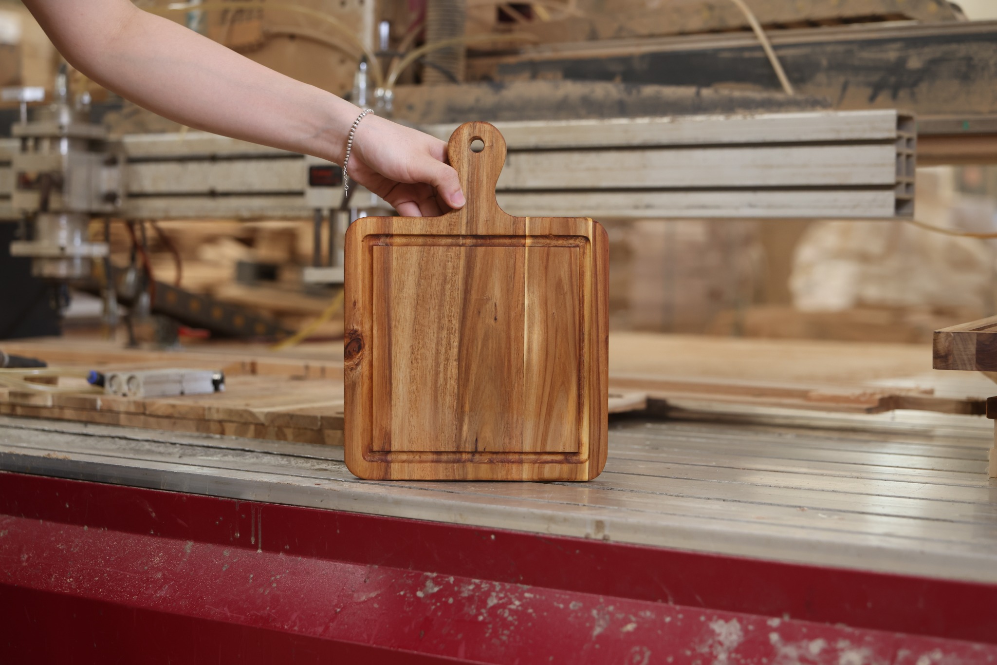 Teak cutting board with a paddle handle, hanging hole and perimeter juice groove