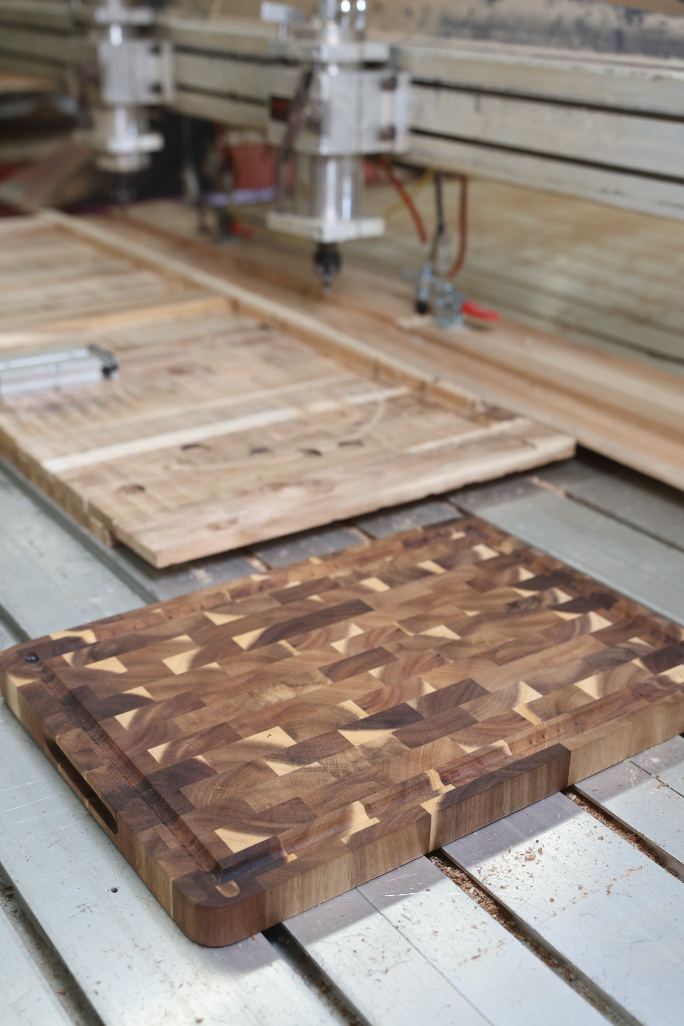 End-grain and edge-grain wooden cutting board samples on a woodworking machine table