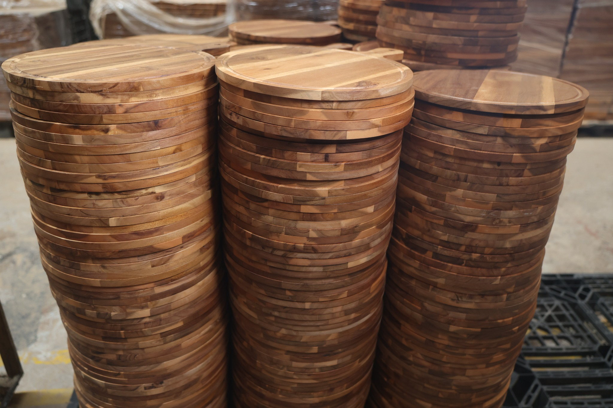 Finished round wooden cutting boards with juice grooves stacked for wholesale orders in Vietnam
