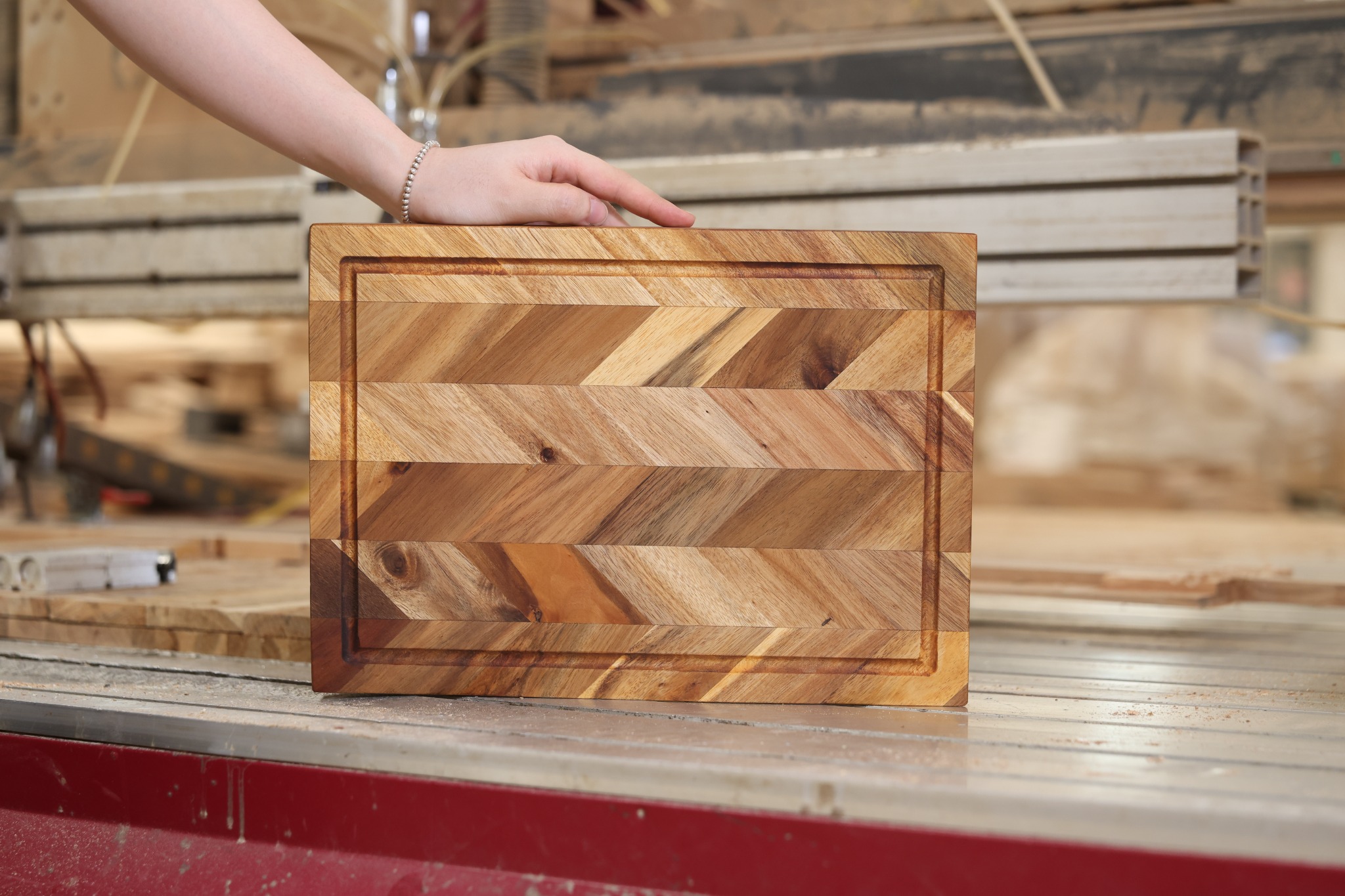 Chevron-pattern wooden cutting board presented at the factory machining table