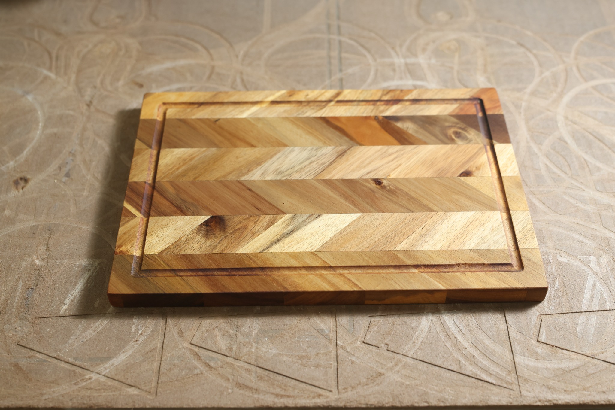 Chevron-pattern wooden cutting board with a continuous juice groove
