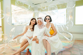 Three women in white posing on inflatable sofa at Supergoop event