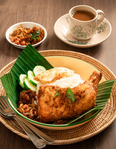 Fried chicken, sambal, and rice on banana leaf with coffee