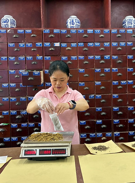 Praticienne prescrivant une formule de pharmacopée chinoise devant une armoire à plantes médicinales, à Chengdu