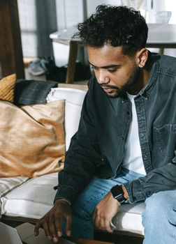 Young man sitting in the couch and working from home on his laptop