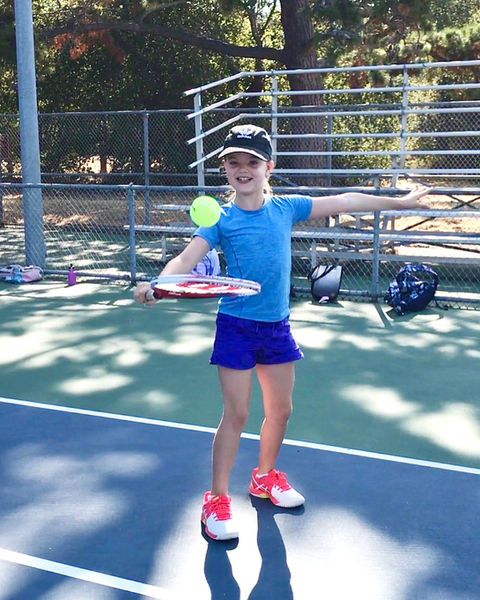 Young girl with tennis rack and ball.
