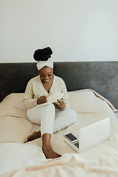 African American woman sitting on her bed working