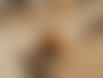 A glass of iced coffee with swirling cream sits on a wooden kitchen counter in warm light. The background is softly blurred.