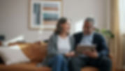 Picture of a happy senior couple using a tablet while sitting on a couch