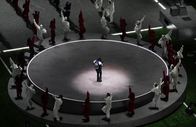 Kendrick Lamar performs on the center of an elevated circular stage surrounded by dancers during the Super Bowl LIX Chiefs vs Eagles Apple Music Halftime Show.