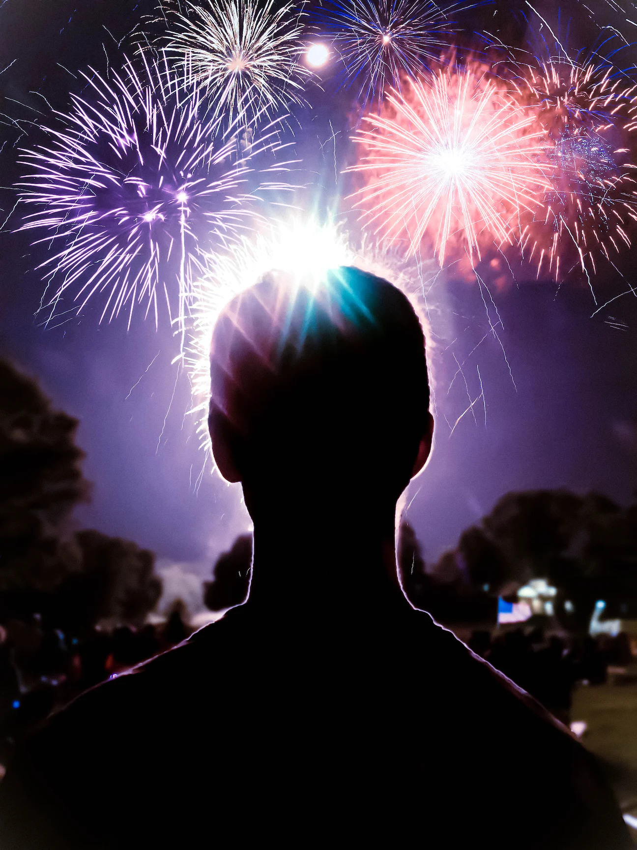 Sillouette of a man outlined by bright sky lit up by fireworks