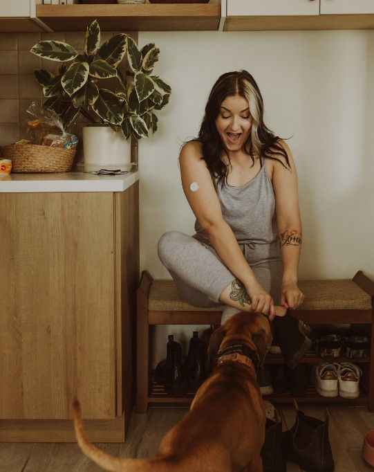 Happy woman with type 2 diabetes wearing continuous glucose monitor CGM going on walk with her dog to improve blood sugar