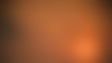 Two parachutists glide across an orange sunset sky.