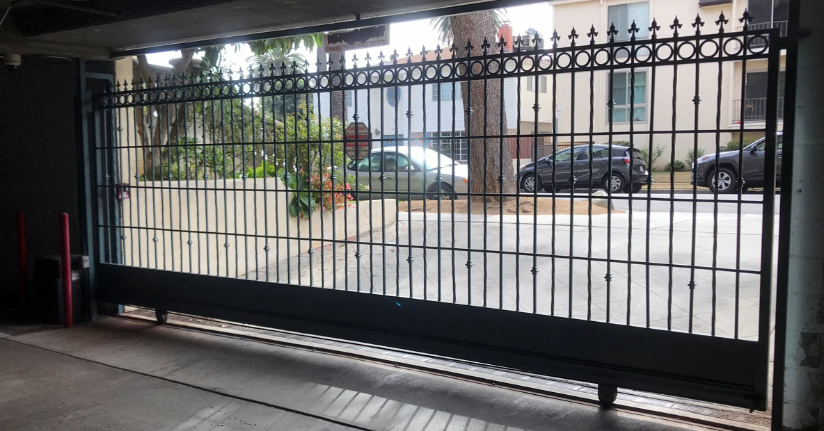 Black iron garage security gate with spear-top pickets at an apartment parking entrance in Panorama City, CA