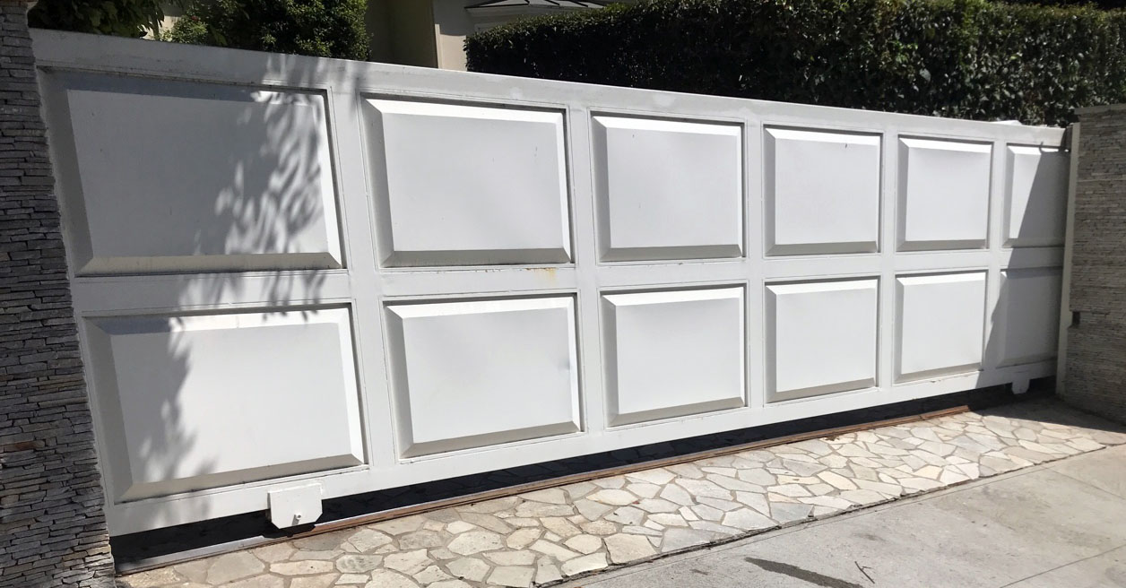 White raised-panel solid slide gate across a residential driveway in Valley Glen, CA