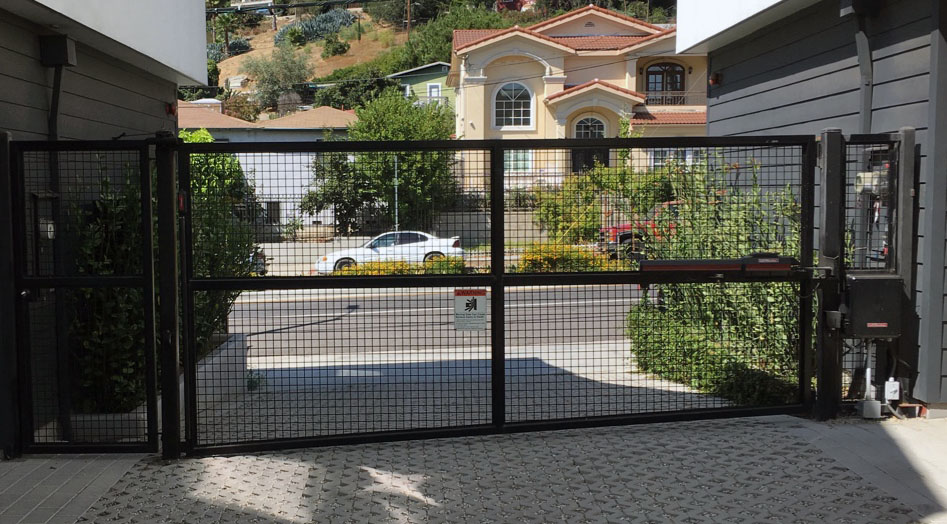 Black steel slide gate with wire mesh panels at a hillside residential driveway in Sun Valley, CA