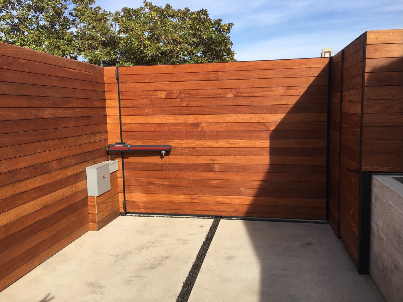 Natural horizontal wood-slat gate and fence with gate operator at a modern home in Eagle Rock, CA