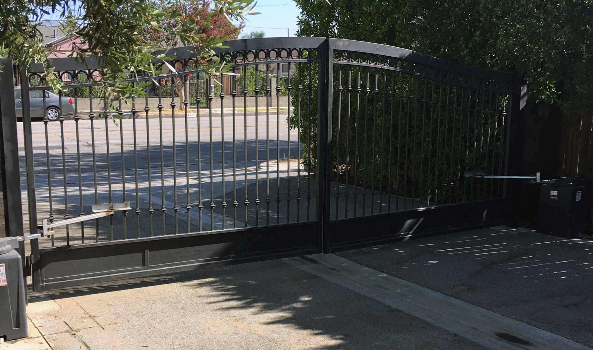 Black iron double swing driveway gate with swing gate operator arms at a residential entry in Winnetka, CA