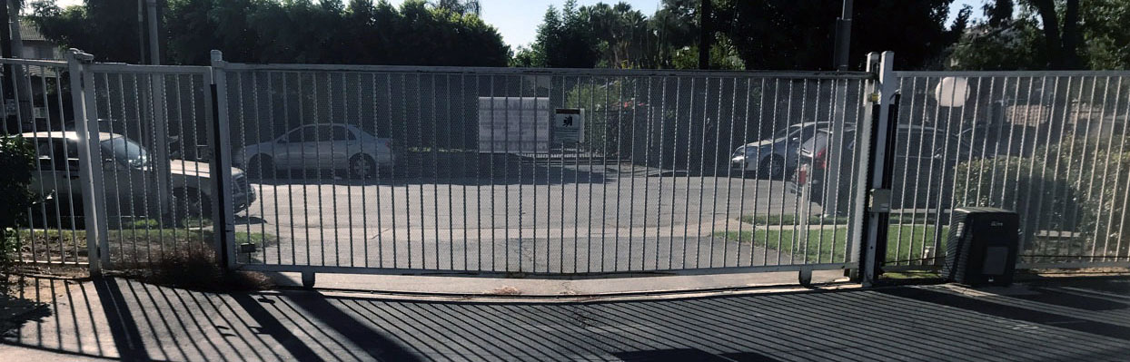 White steel double swing security gate with gate operator at a parking lot entrance in North Hollywood, CA