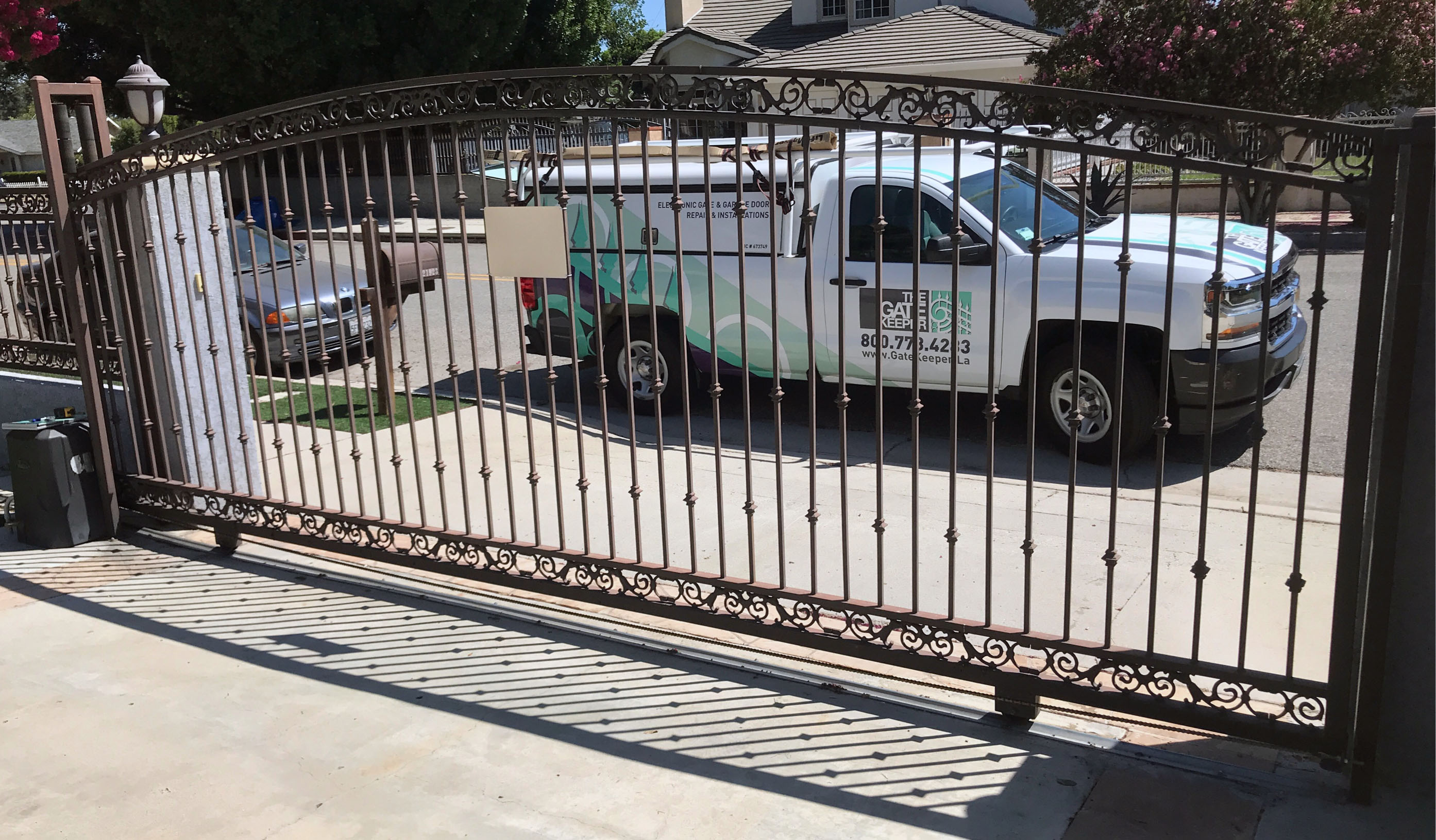 Black wrought iron slide gate with scroll top across a residential driveway in Northridge, CA