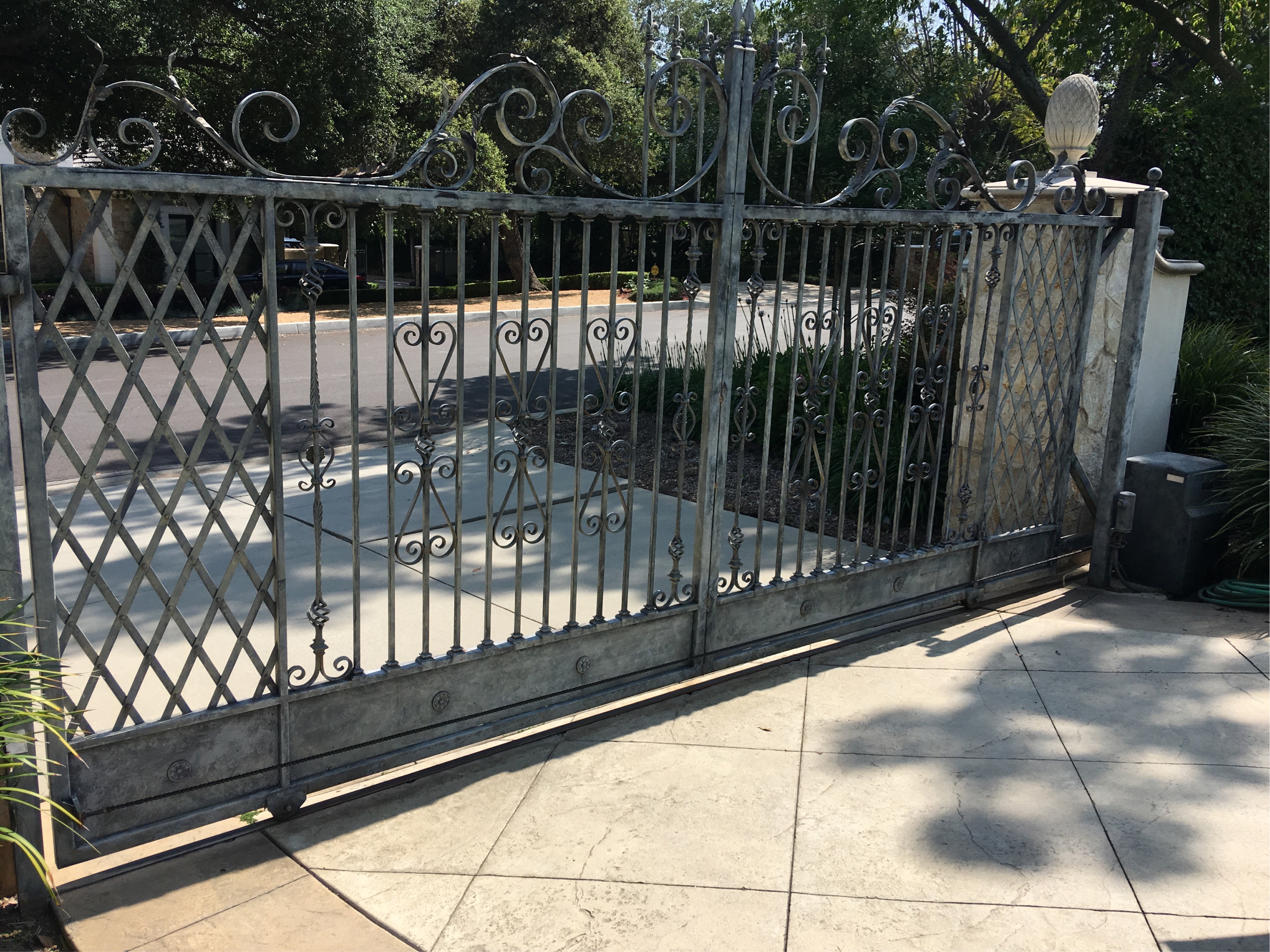 Silver iron slide gate with lattice pattern and scroll top at an estate driveway in Somis, CA