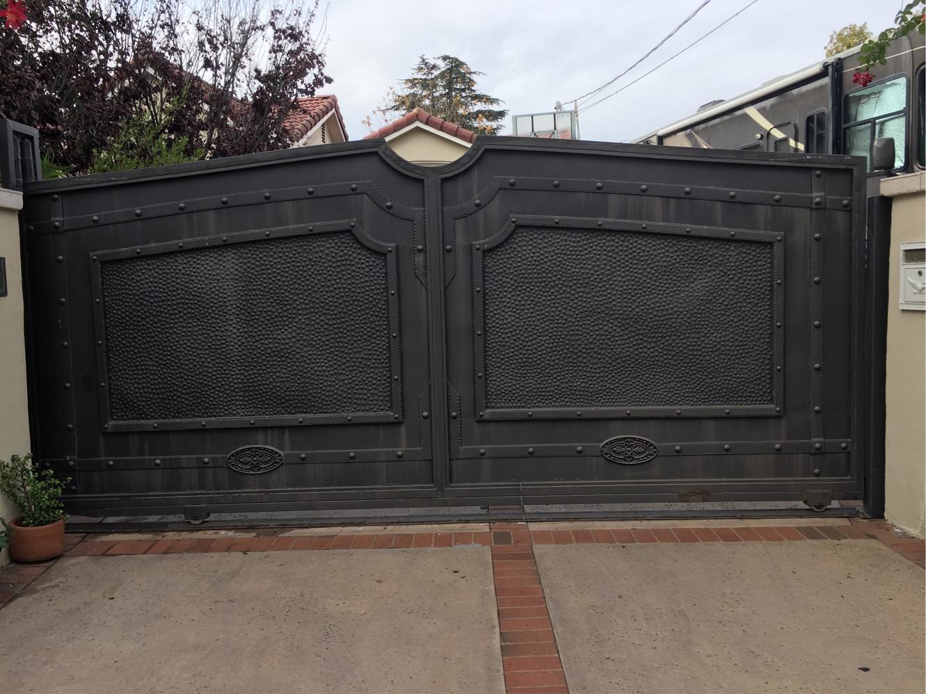 Black solid-panel double driveway gate with raised molding and medallions in Sunland, CA