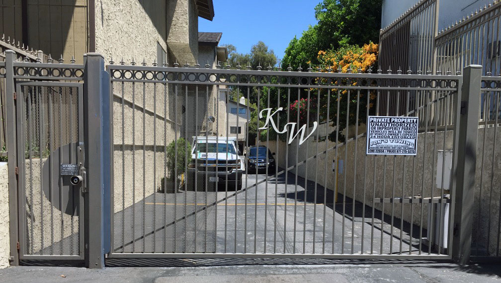 Gray iron slide gate with monogram letters at an apartment parking entrance in Van Nuys, CA
