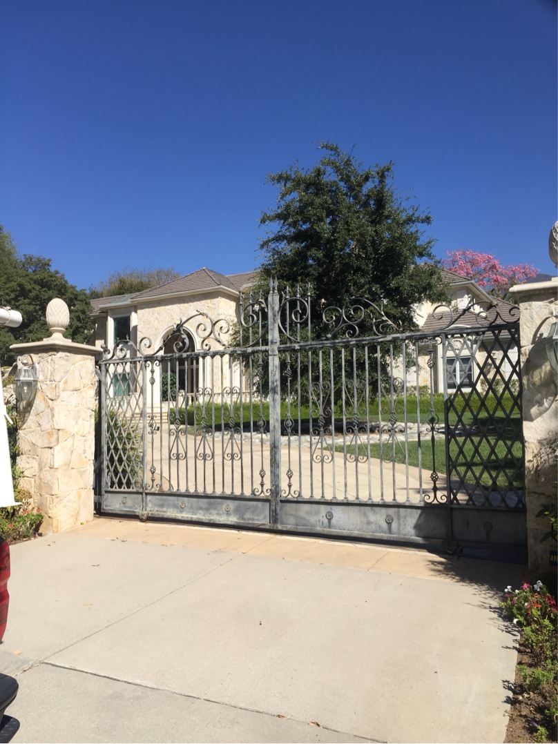 White iron slide gate with scroll top at a Spanish-style home in San Fernando, CA