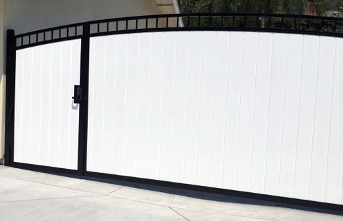 Arched white solid-panel driveway gate in a black steel frame in Valley Glen, CA