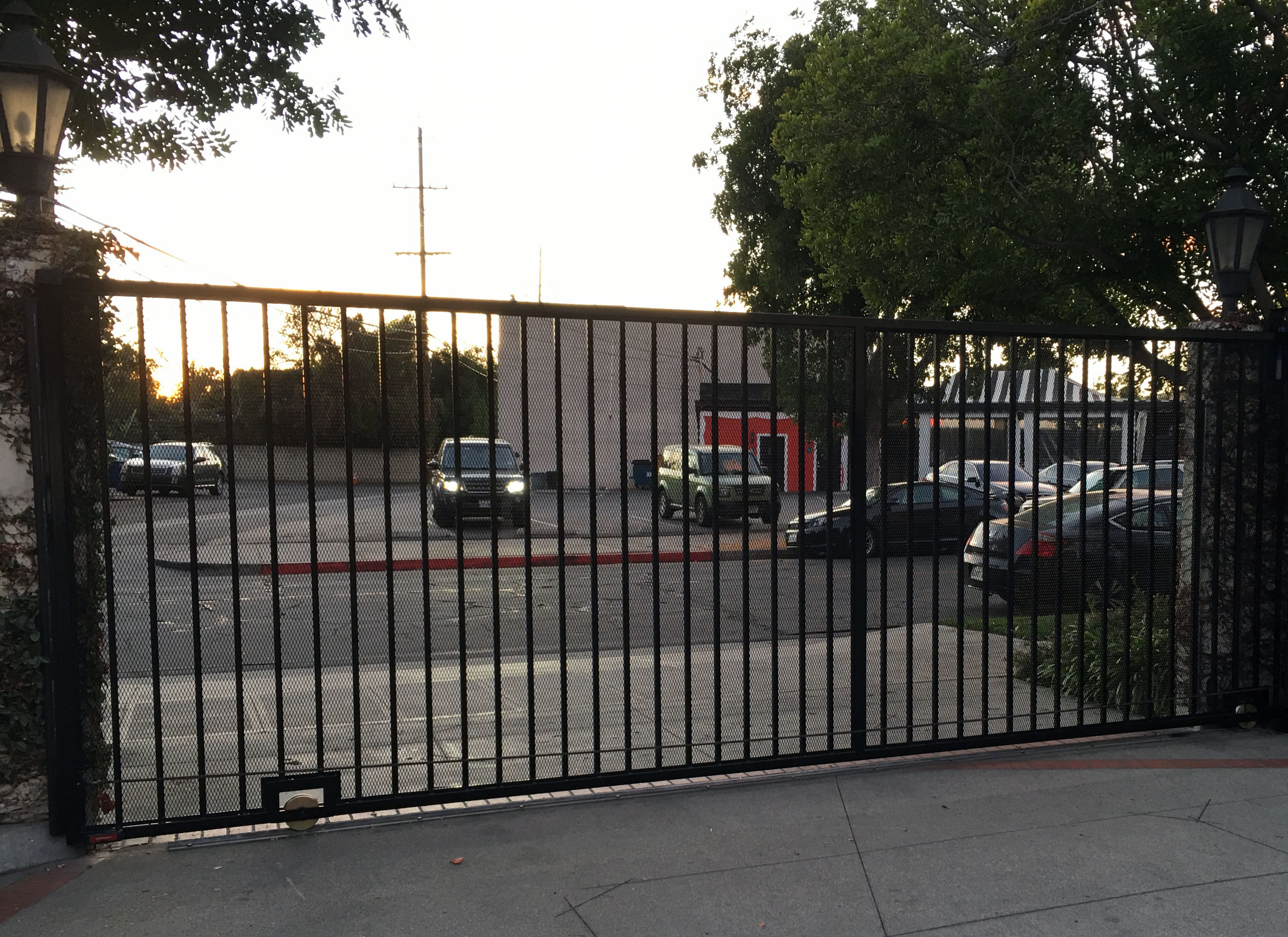 Black iron slide gate across a commercial driveway along a busy street in Sun Valley, CA